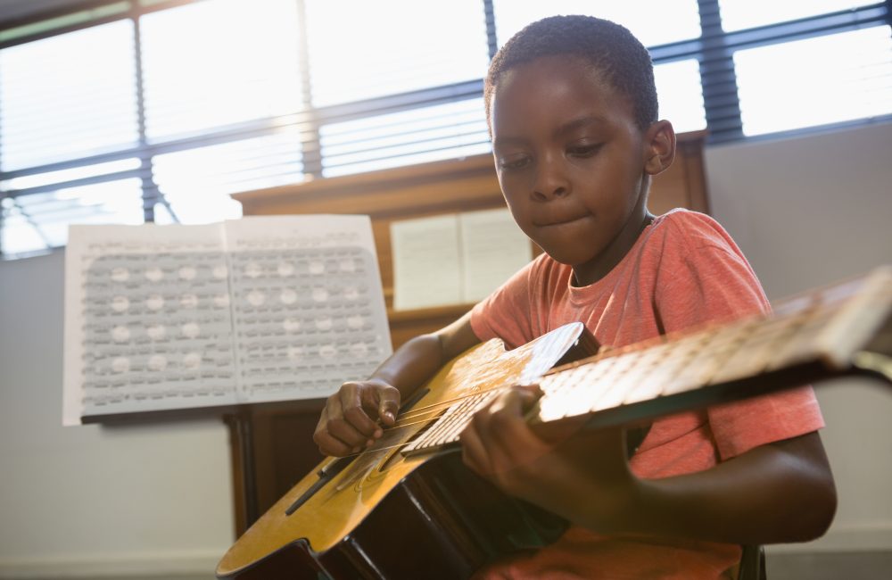 Boy playing guitar in class at music school